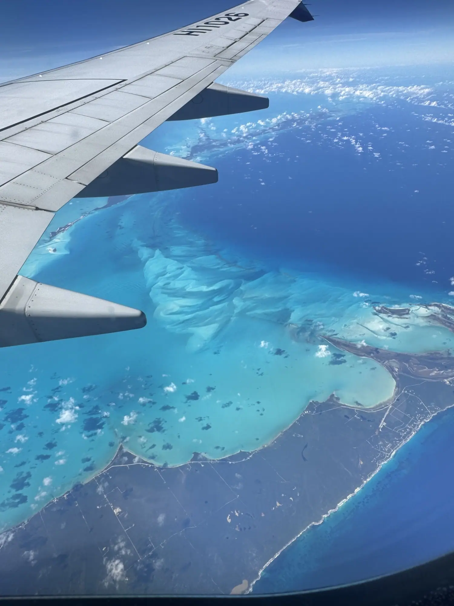 Asa do avião sobre mar azul-turquesa